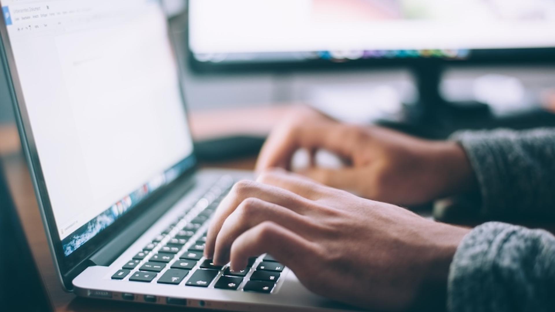 Hands typing on laptop