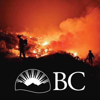 Two firefighters silhouetted against a background of a wildfire with a British Columbia logo.